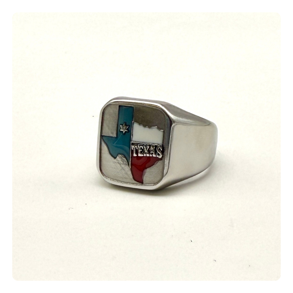 A silver signet ring featuring an inlaid Texas flag design with blue, red, and white sections, and the word 'TEXAS' engraved on the face of the ring.